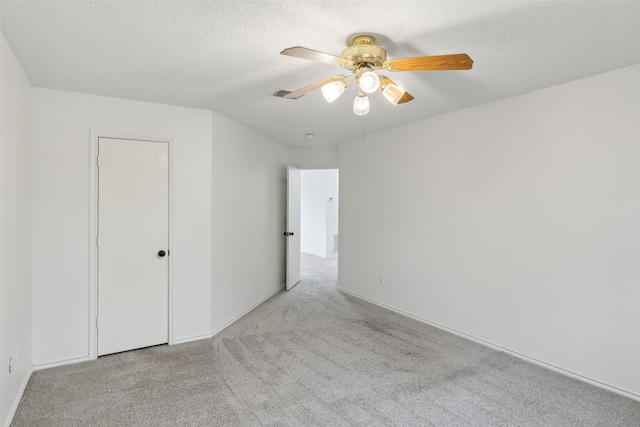 unfurnished bedroom with ceiling fan, light colored carpet, and a textured ceiling