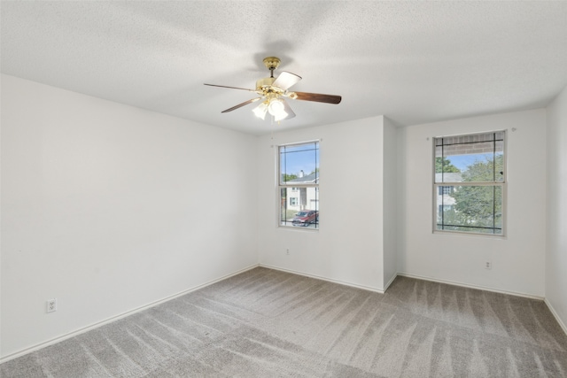 carpeted spare room featuring ceiling fan, a textured ceiling, and a healthy amount of sunlight