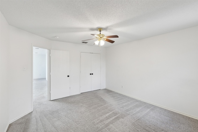 unfurnished bedroom featuring ceiling fan, light colored carpet, and a textured ceiling