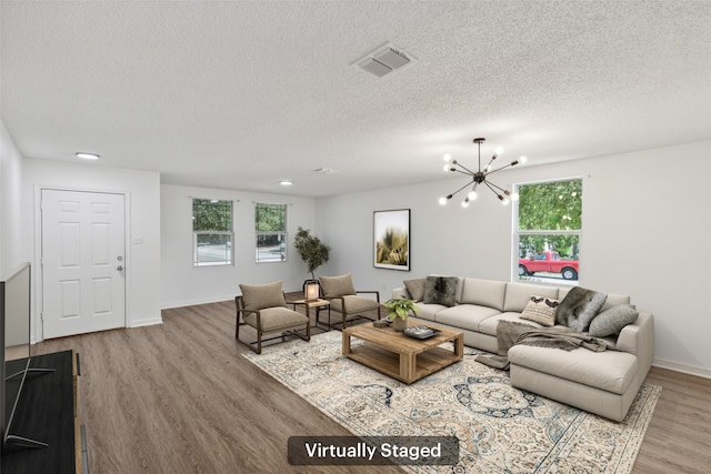 living room featuring a textured ceiling, light wood-type flooring, a chandelier, and a healthy amount of sunlight