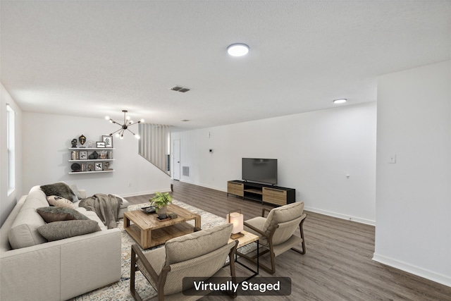 living room featuring a notable chandelier, a textured ceiling, and hardwood / wood-style flooring