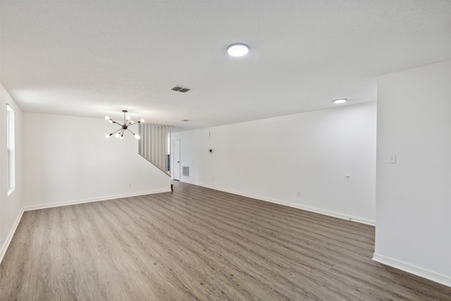 spare room with a notable chandelier, a textured ceiling, and hardwood / wood-style flooring