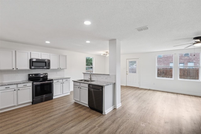 kitchen with white cabinets, appliances with stainless steel finishes, light wood-type flooring, and a wealth of natural light