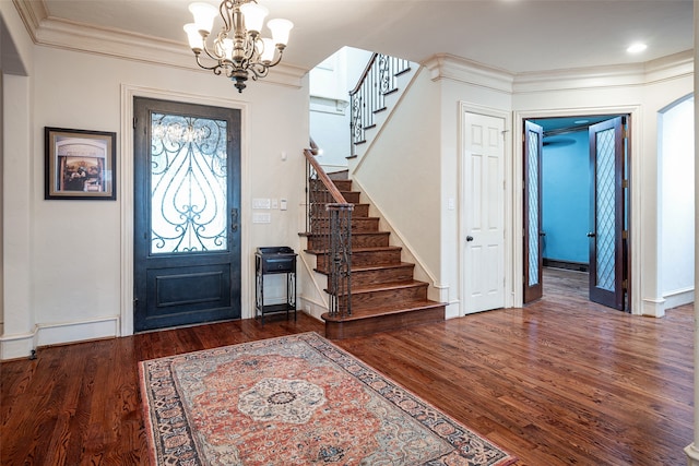 foyer with dark wood-type flooring, an inviting chandelier, and crown molding