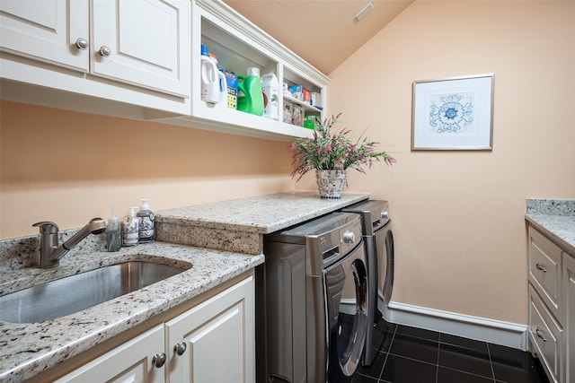 laundry room featuring dark tile patterned flooring, cabinets, independent washer and dryer, and sink