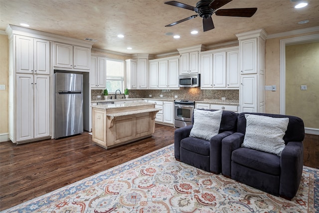 kitchen with dark hardwood / wood-style flooring, a center island, stainless steel appliances, white cabinetry, and ceiling fan