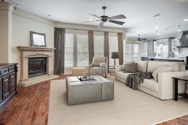 living room with wood-type flooring, crown molding, and ceiling fan