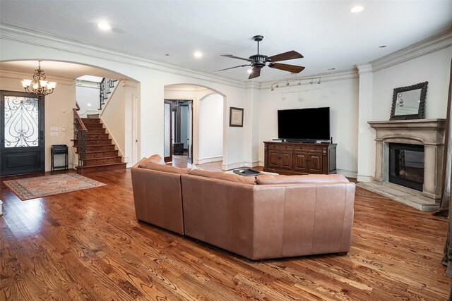 living room featuring rail lighting, ceiling fan with notable chandelier, hardwood / wood-style flooring, and crown molding