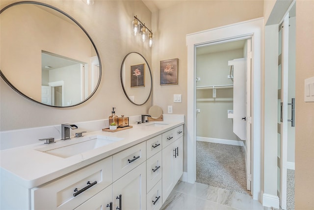 full bathroom with double vanity, marble finish floor, baseboards, and a sink