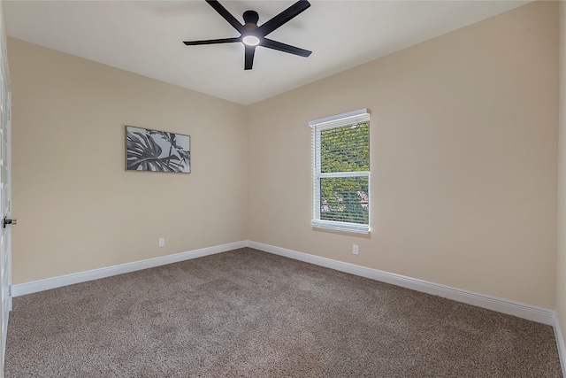 carpeted spare room featuring baseboards and a ceiling fan