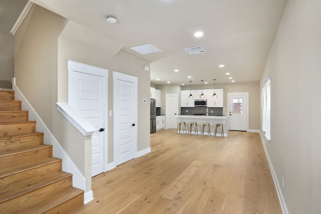 unfurnished living room featuring recessed lighting, visible vents, stairway, light wood-style floors, and baseboards