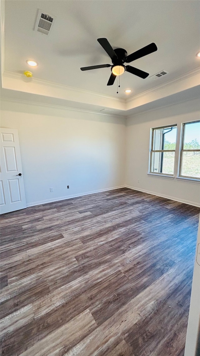 unfurnished room featuring dark wood-type flooring, ornamental molding, a tray ceiling, and ceiling fan