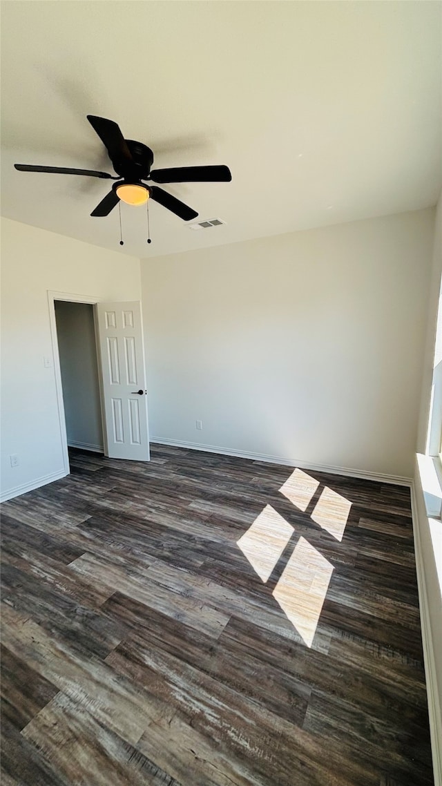 empty room with ceiling fan and dark hardwood / wood-style flooring