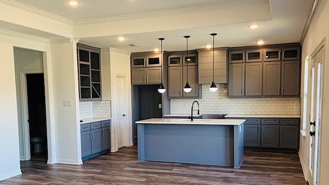 kitchen with an island with sink, decorative backsplash, dark hardwood / wood-style floors, pendant lighting, and ornamental molding