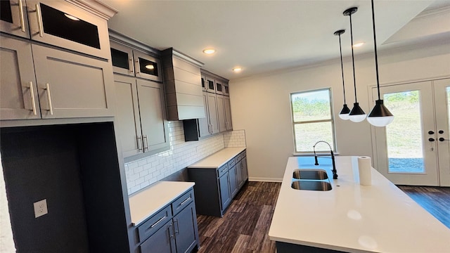 kitchen featuring pendant lighting, sink, crown molding, dark hardwood / wood-style flooring, and decorative backsplash