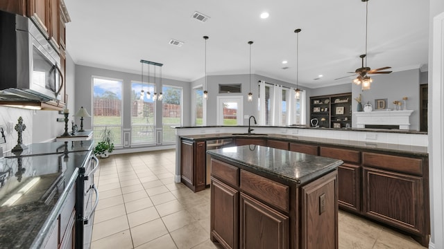 kitchen with a center island, stainless steel appliances, crown molding, decorative light fixtures, and ceiling fan with notable chandelier