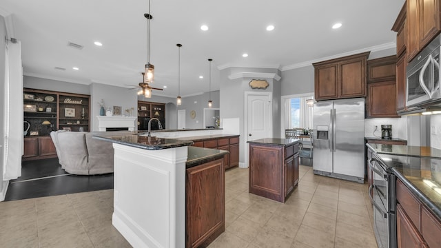 kitchen with appliances with stainless steel finishes, a kitchen island with sink, crown molding, ceiling fan, and decorative light fixtures