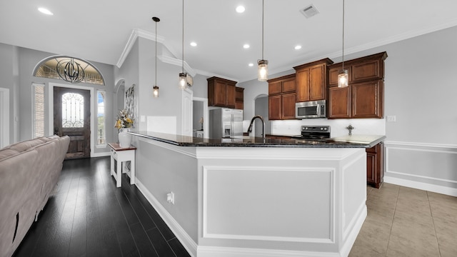 kitchen with a large island, pendant lighting, stainless steel appliances, and light hardwood / wood-style floors