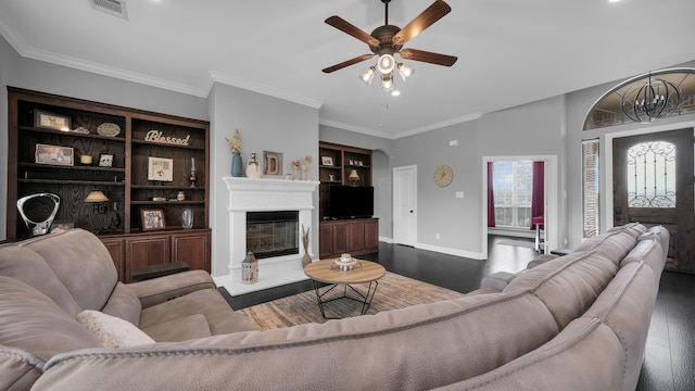 living room with ceiling fan, crown molding, dark wood-type flooring, and built in shelves