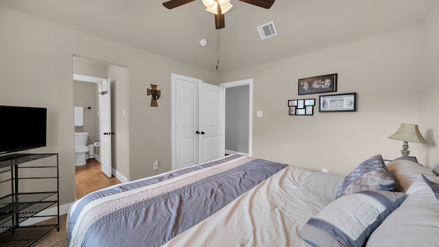 tiled bedroom featuring ceiling fan, a closet, lofted ceiling, and ensuite bath