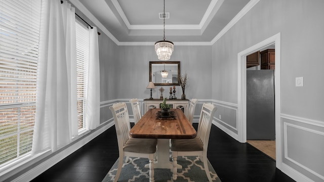 dining room with a notable chandelier, dark wood-type flooring, and a tray ceiling