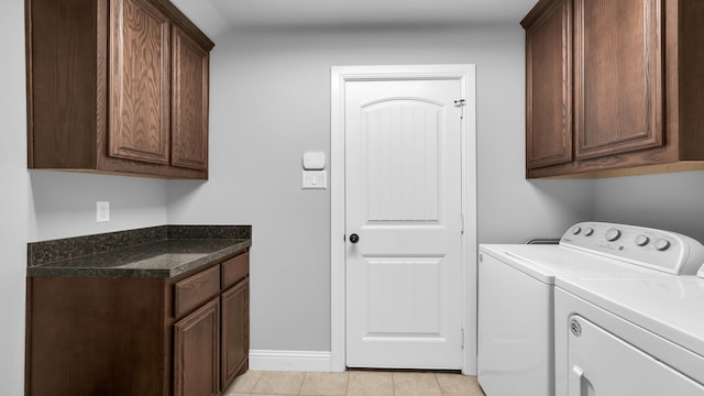 laundry room with washer and clothes dryer, light tile patterned flooring, and cabinets