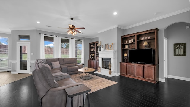 living room with dark hardwood / wood-style floors, built in features, ceiling fan, and crown molding