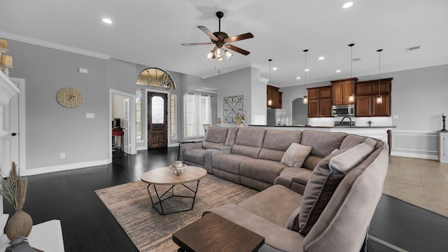 living room with dark hardwood / wood-style floors, ceiling fan, ornamental molding, and sink