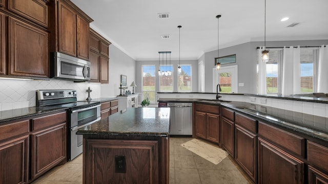 kitchen with sink, stainless steel appliances, backsplash, pendant lighting, and a kitchen island