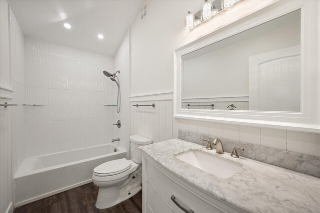 full bathroom featuring vanity, hardwood / wood-style floors, tasteful backsplash, toilet, and tiled shower / bath combo