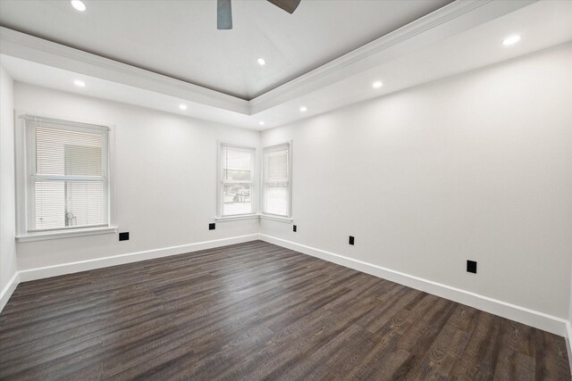 empty room with dark wood-type flooring, a raised ceiling, and ceiling fan