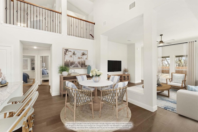 dining room with a towering ceiling, dark hardwood / wood-style flooring, and ceiling fan