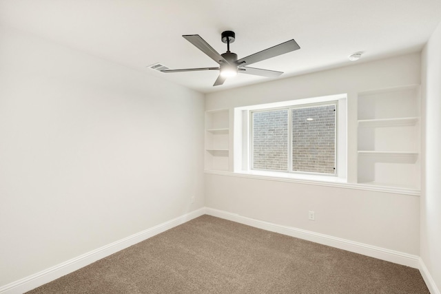 carpeted empty room with ceiling fan and built in shelves