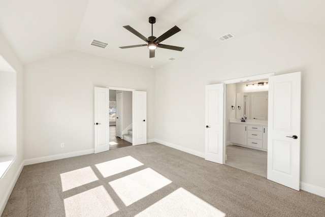 unfurnished bedroom featuring vaulted ceiling, ensuite bath, light colored carpet, and ceiling fan