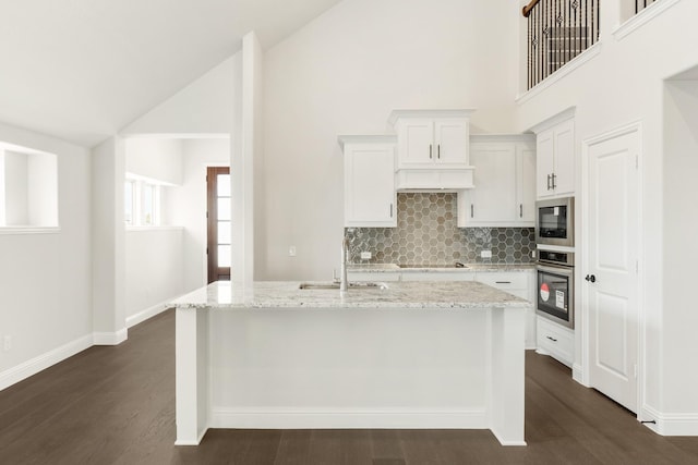 kitchen with stainless steel appliances, an island with sink, high vaulted ceiling, backsplash, and sink