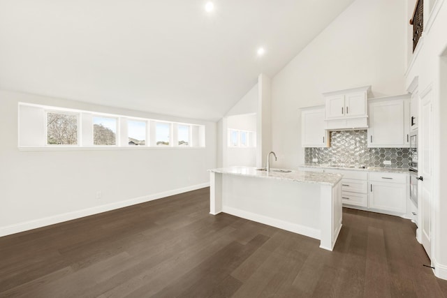 kitchen featuring a center island with sink, stainless steel appliances, high vaulted ceiling, sink, and tasteful backsplash