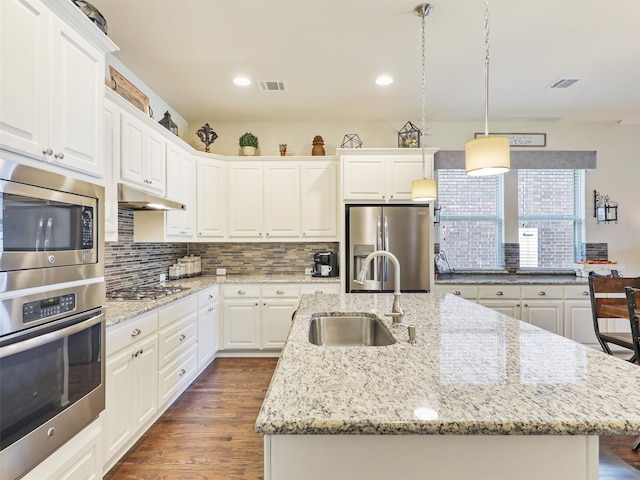 kitchen featuring an island with sink, stainless steel appliances, sink, and white cabinetry