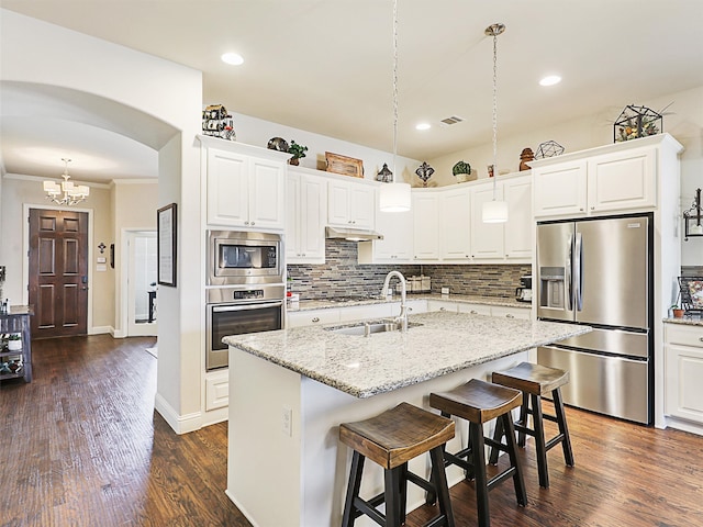 kitchen with a kitchen island with sink, white cabinetry, appliances with stainless steel finishes, decorative light fixtures, and dark hardwood / wood-style flooring