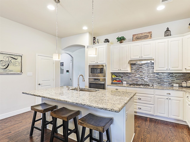 kitchen with decorative light fixtures, appliances with stainless steel finishes, a kitchen island with sink, and sink