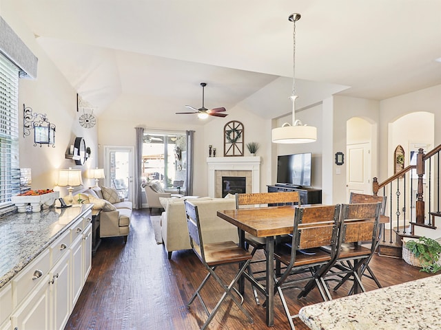 dining room with lofted ceiling, ceiling fan, a tile fireplace, and dark hardwood / wood-style floors