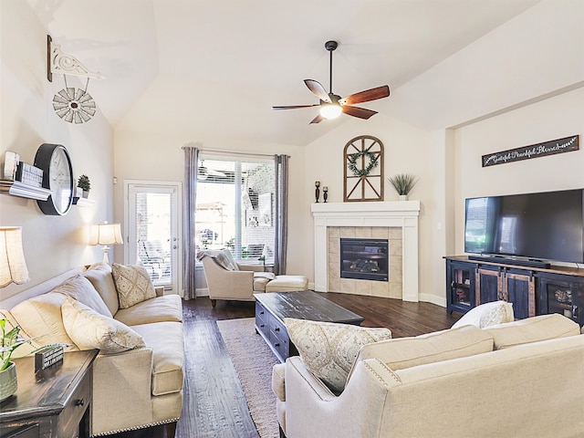 living room with lofted ceiling, ceiling fan, a tiled fireplace, and dark wood-type flooring