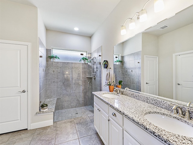 bathroom featuring tiled shower, vanity, and tile patterned flooring