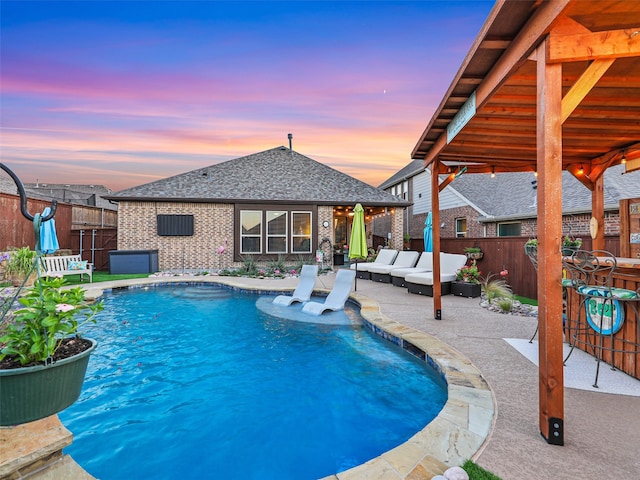 pool at dusk featuring a patio and an outdoor hangout area