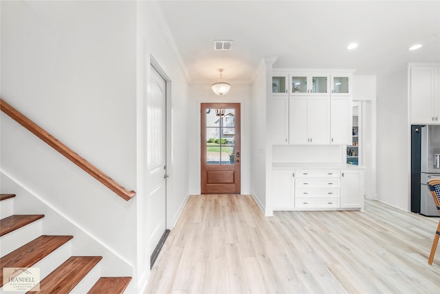 foyer entrance featuring ornamental molding and light wood-type flooring