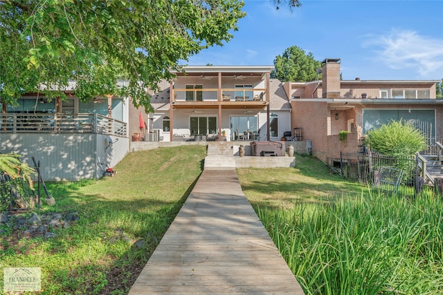 rear view of property featuring ceiling fan, a lawn, and a patio area