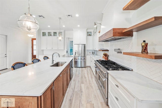 kitchen with a kitchen island with sink, white cabinetry, stainless steel appliances, sink, and decorative backsplash