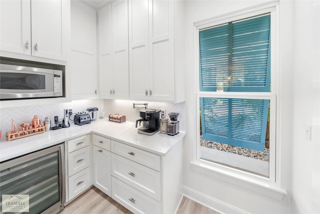 kitchen with beverage cooler, white cabinetry, and a healthy amount of sunlight