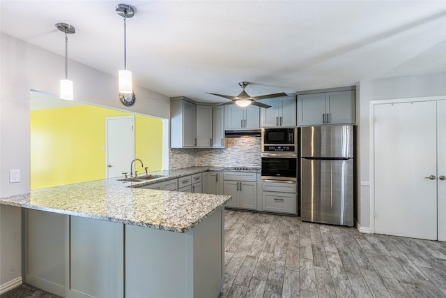 kitchen featuring decorative light fixtures, ceiling fan, stainless steel appliances, and kitchen peninsula