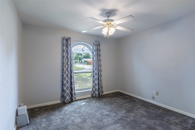 spare room featuring ceiling fan and dark colored carpet