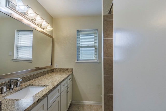 bathroom with tile patterned flooring, vanity, and tiled shower